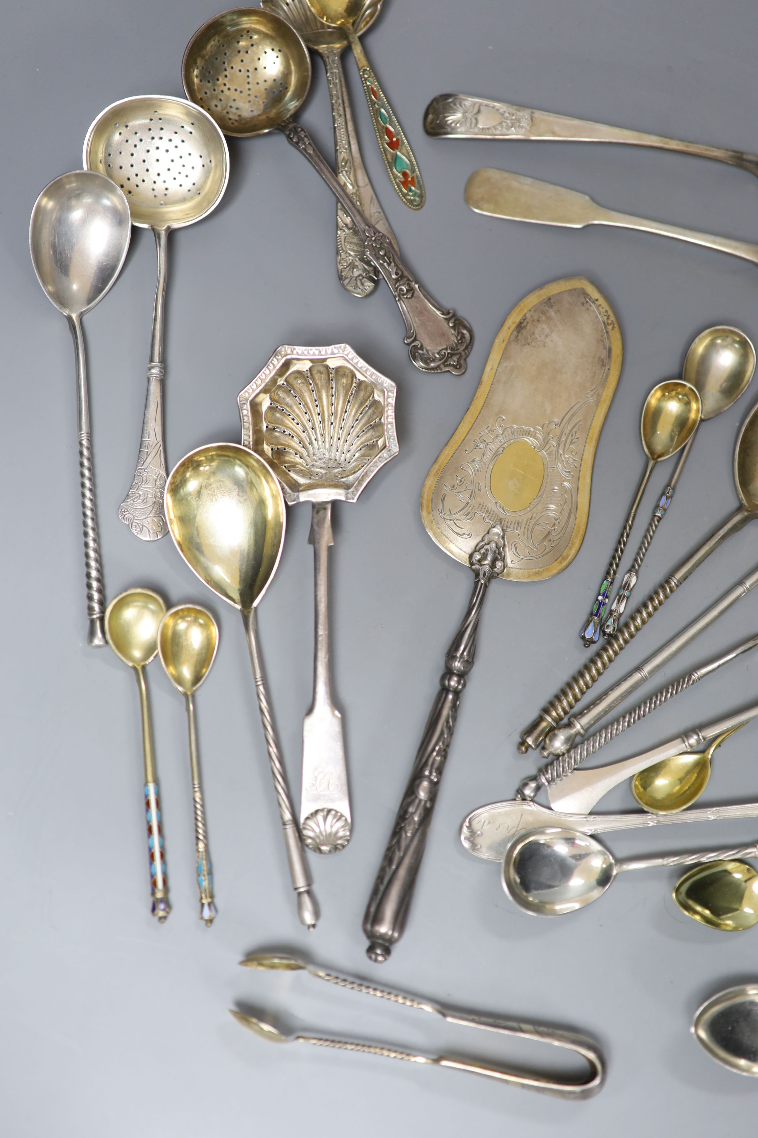 A late 19th century Russian 84 zolotnik tea strainer, a Russian cake slice and sugar sifter and a group of other Russian flatware including enamelled teaspoons
